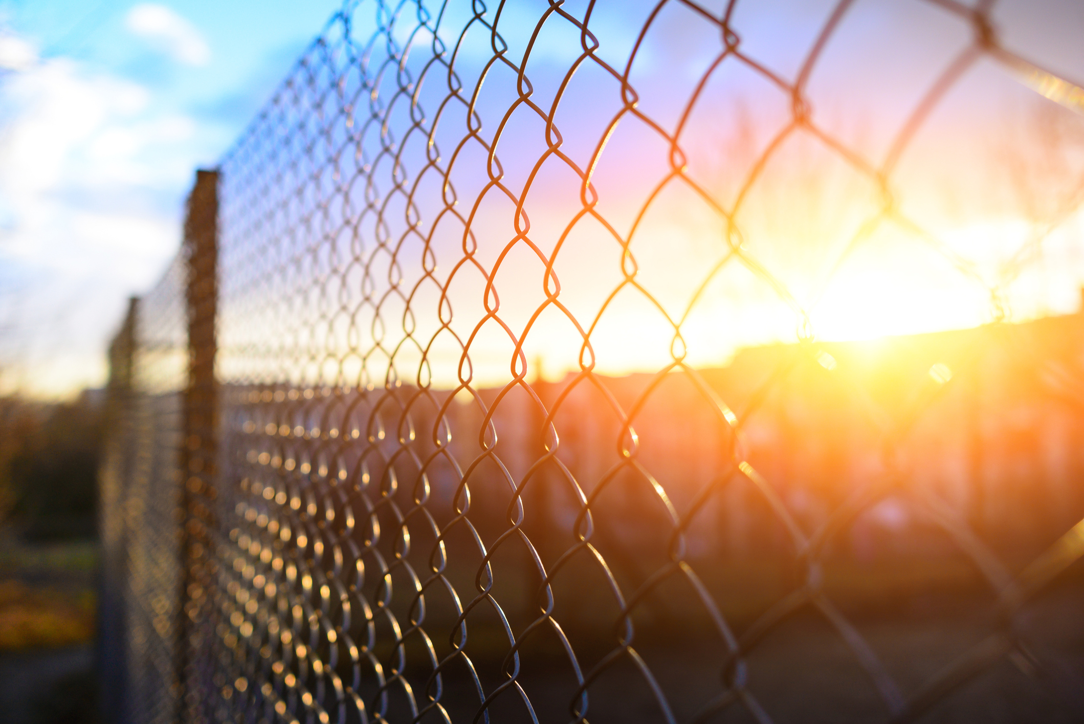 a chain link fence with a pittsburgh sun in the background